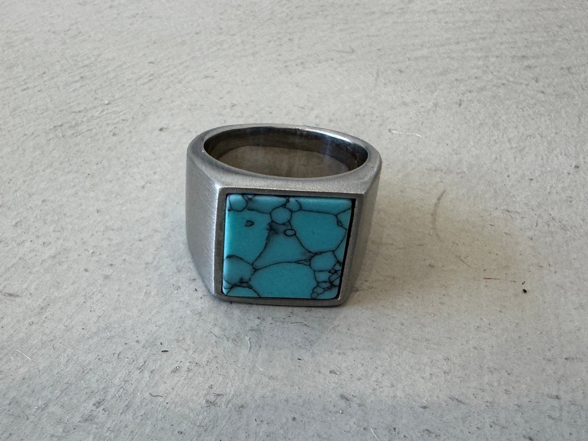 Silver ring with a turquoise stone on a light gray surface