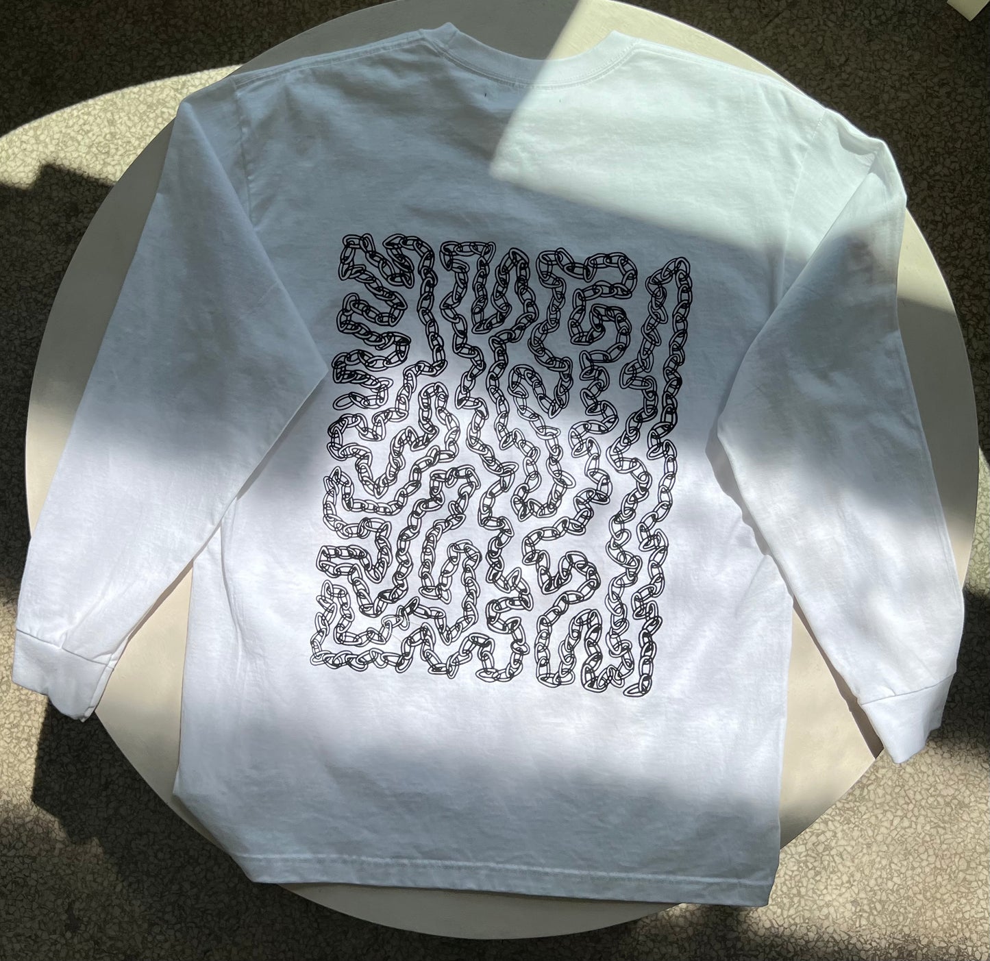 back of shirt - black and white graphic print of chain link curves filling the majority of the back of the shirt