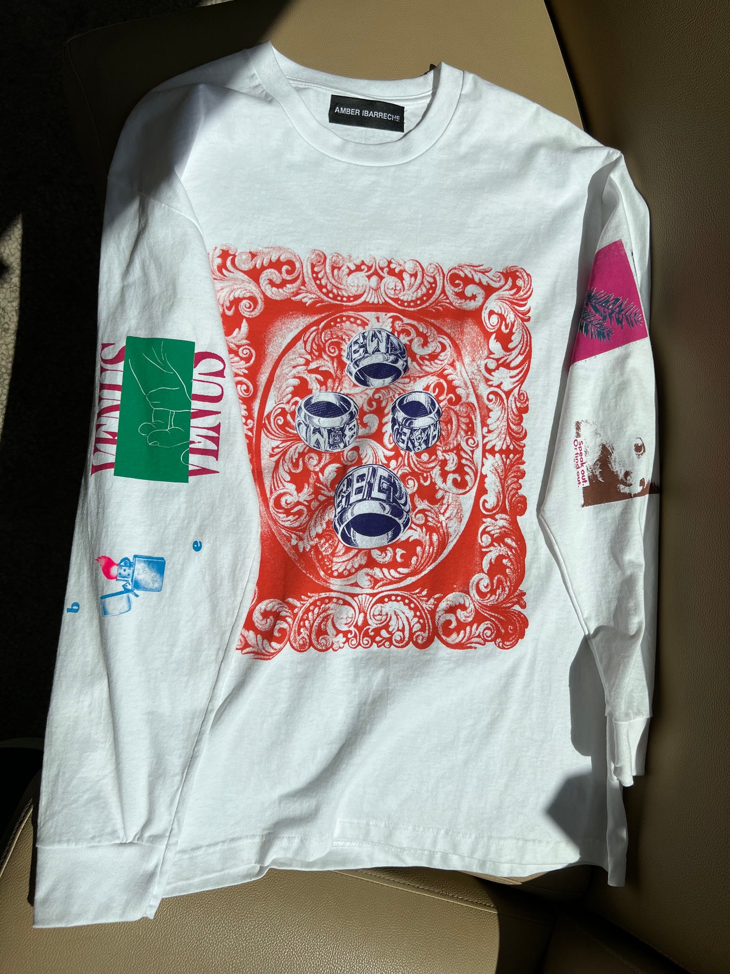 white cotton long sleeve shirt with hand printed collage work down the front and sleeves the left sleeve has a sketch of a lighter with a neon pink flame, closer to the shoulder is the word venus in all caps split by a green rectangle with a white sketch of a hand, palm up